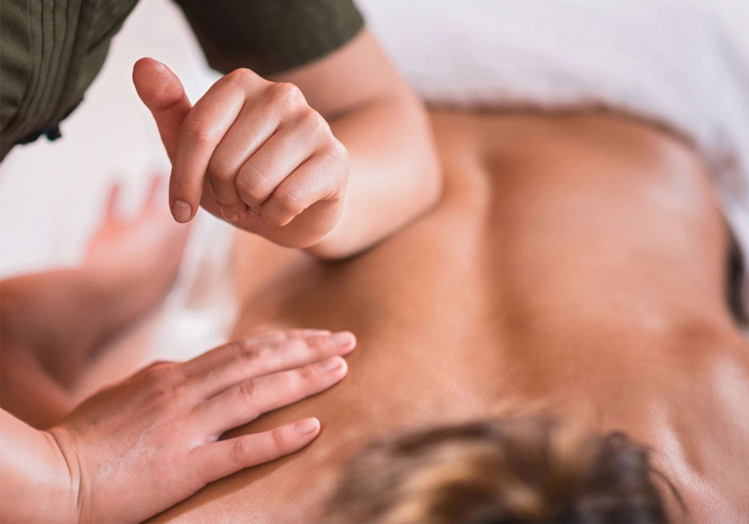 Main prodiguant un massage sur le dos d’une personne allongée, ambiance détente, arrière-plan flou.